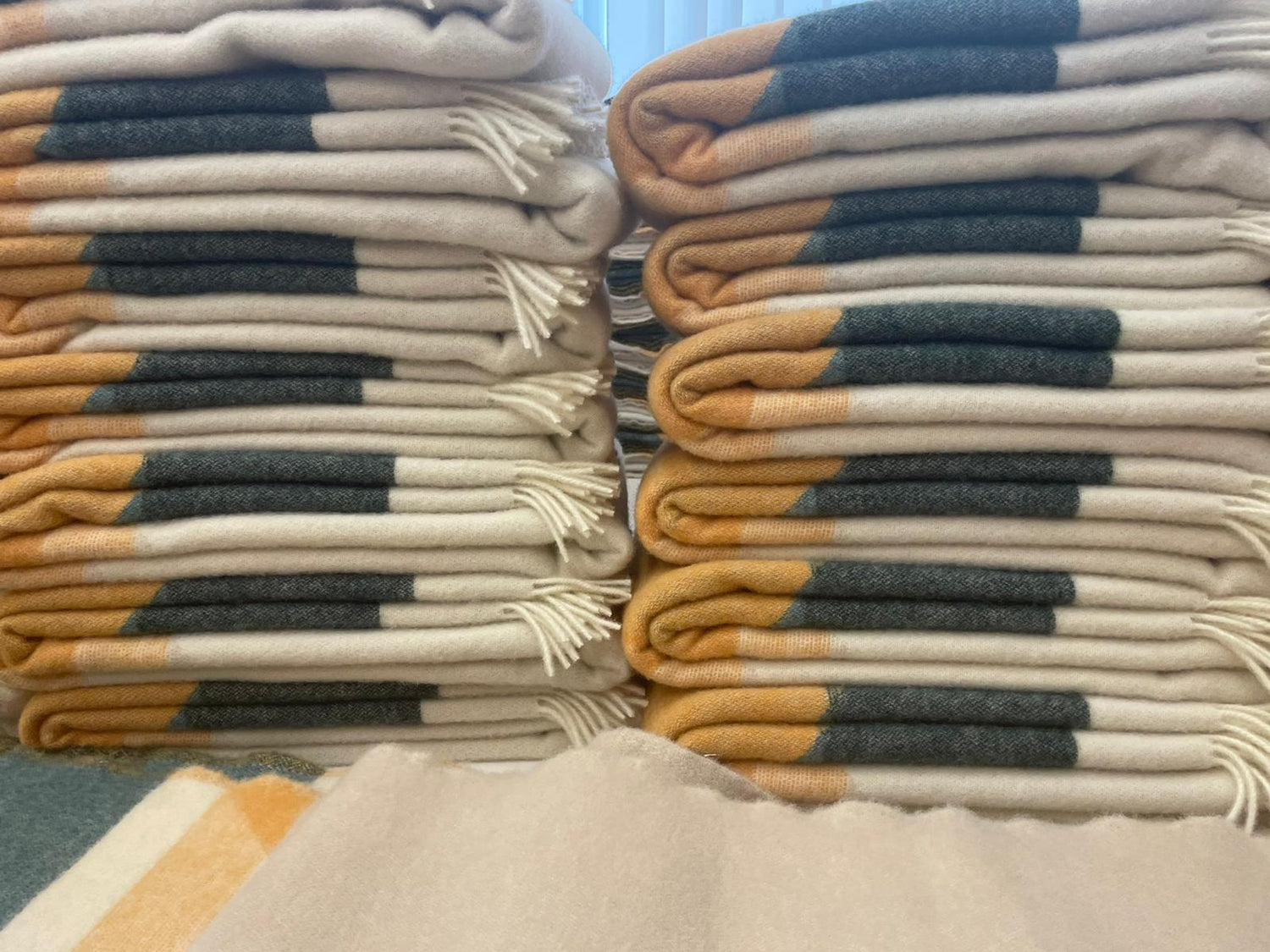 Mehrere übereinandergestapelte HIMALAYA Wolldecken von Steppenwolle liegen in der Produktion bereit.