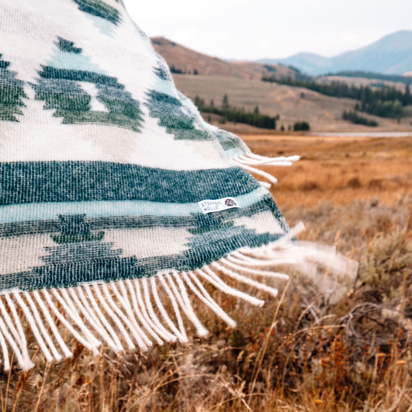 Fransen einer gemusterten Wolldecke wehen im Wind